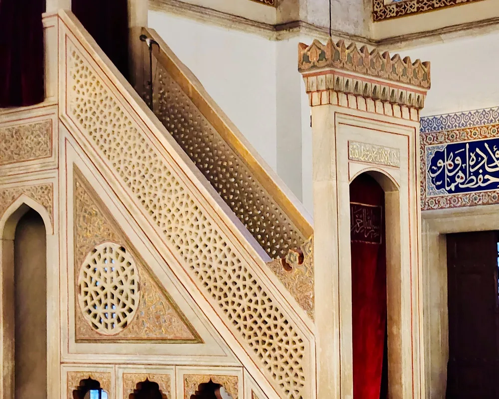 The carved minbar of a traditional mosque, with tilework alongside